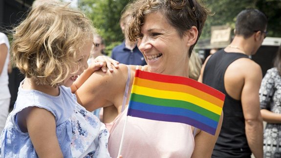 Tochter mit Regenbogenflagge auf dem Arm der Mutter